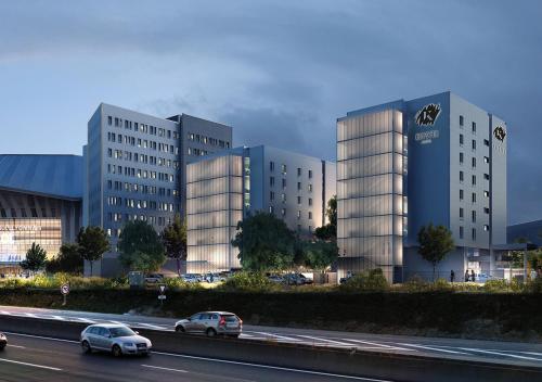 a group of buildings with cars on a highway at KOPSTER Hotel Lyon Groupama Stadium in Décines-Charpieu