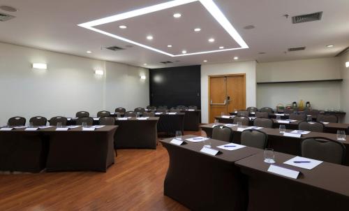 a conference room with tables and chairs and a screen at ibis Campinas in Campinas
