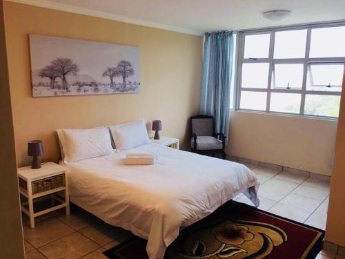 a bedroom with a white bed and a window at Strandburg Holiday Apartments in Amanzimtoti