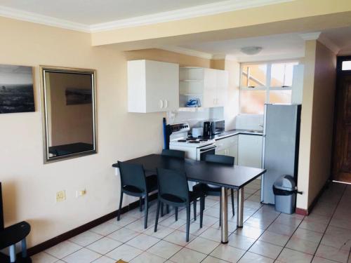 a kitchen with a table and chairs and a refrigerator at Strandburg Holiday Apartments in Amanzimtoti