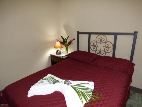 a bedroom with a red bed with a robe on it at Tropical Housing by El Rodeo - Calle El Manglar in Puerto Jiménez