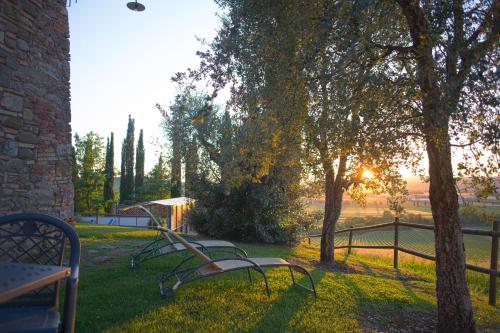 two park benches sitting in the grass near a fence at Residenza Storica Casale Pozzuolo in Cinigiano