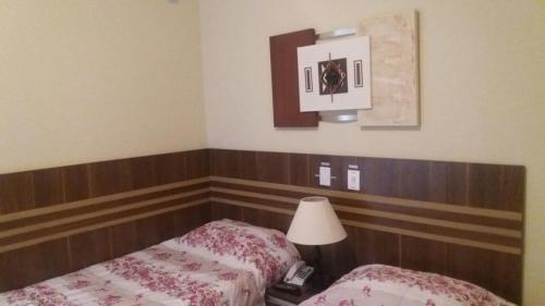 a hotel room with two beds and a lamp at San Marino Hotel in São José dos Campos