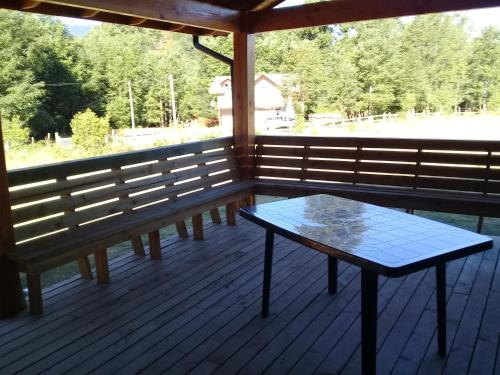 a screened porch with a table and benches on it at Cabañas Los Canelos Pucon, Hermosa Granja de 20 hectaréas a orillas del Río Liucura in Pucón