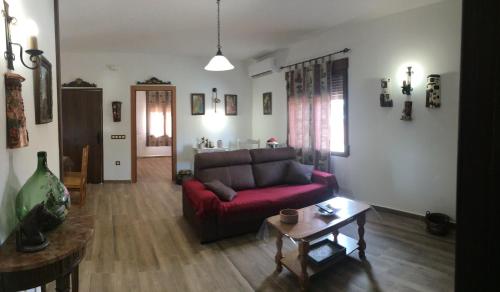 a living room with a red couch and a table at El Retiro de Cervantes in Ossa de Montiel