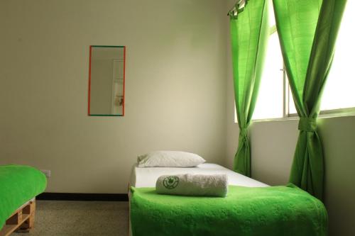 a bedroom with a bed with a green ottoman and a window at Hostal Paz y Vida in Medellín