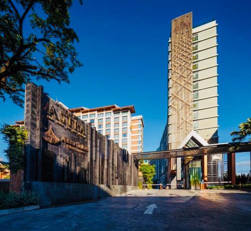 a tall building with a building in the background at Astra Suites Central in Chiang Mai
