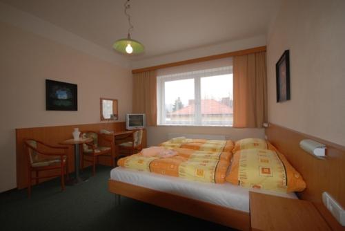 a bedroom with a bed and a table and a window at Penzion Růže in Humpolec