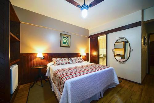 a bedroom with a large bed and a mirror at Pousada dos Pinhos in Pedra Azul
