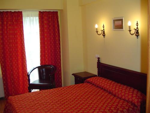 a bedroom with a red bed and a window at Hotel Europa in Ploieşti
