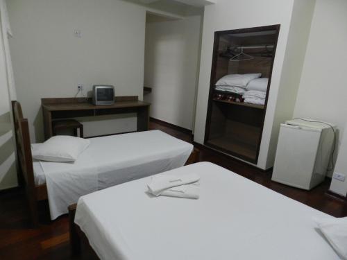 a hotel room with two beds and a mirror at Príncipe Hotel in Poços de Caldas