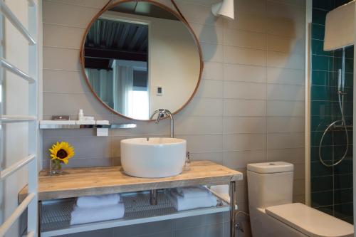 a bathroom with a toilet a sink and a mirror at 250 Main Hotel in Rockland