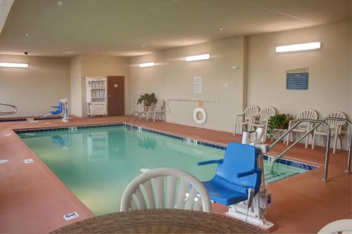 a swimming pool with a blue chair and chairs at Cobblestone Hotel and Suites - Jefferson in Jefferson