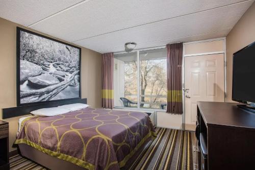een hotelkamer met een bed en een groot raam bij Super 8 by Wyndham Sevierville Riverside in Sevierville