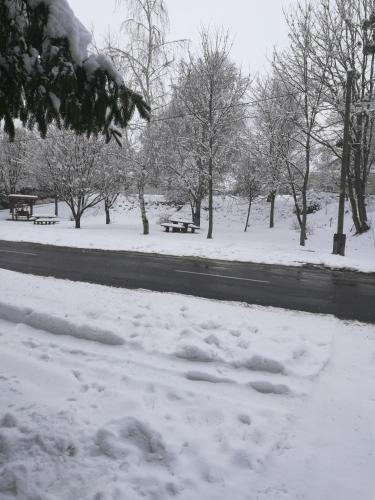 a snow covered park with benches and a road at Koppány Lovasudvar in Bakonykoppány
