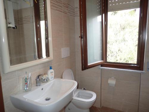 Un baño con lavabo, inodoro y ventana. en Casetta al Mare, en Giustenice