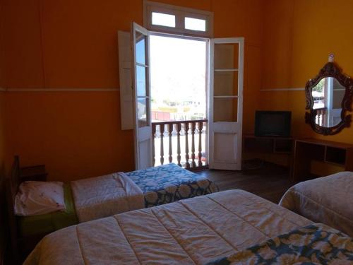 a bedroom with two beds and a window and a mirror at Hospederia Taltal in Taltal