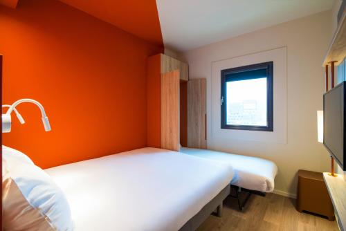 two beds in a room with an orange wall at ibis budget Stein Maastricht in Stein