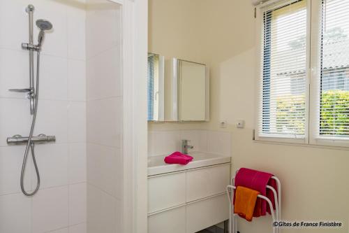 a white bathroom with a shower and a sink at La maison du port in Plougasnou