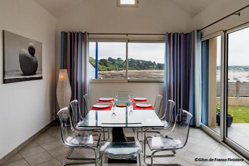 a dining room with a table and chairs and windows at La maison du port in Plougasnou