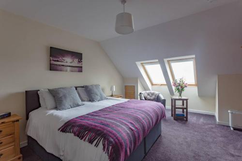 1 dormitorio con 1 cama grande con manta morada en Ardenlee Self Catering Apartment en Borve