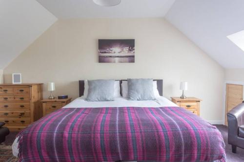 a bedroom with a large bed with a purple blanket at Ardenlee Self Catering Apartment in Borve