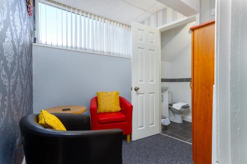 a living room with a red chair and a table at Adelaide Lodge - Town Centre - Opposite Winter Gardens in Blackpool