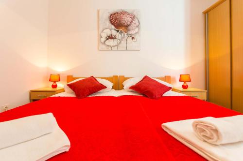 a bedroom with a red bed with two red pillows at Apartments Afrodita in Dubrovnik