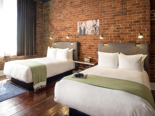 a hotel room with two beds and a brick wall at The Old No. 77 Hotel & Chandlery in New Orleans