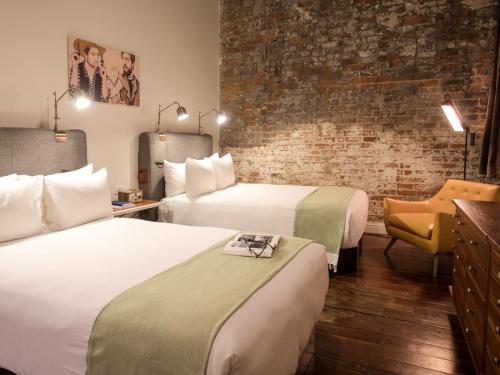 a hotel room with two beds and a brick wall at The Old No. 77 Hotel & Chandlery in New Orleans