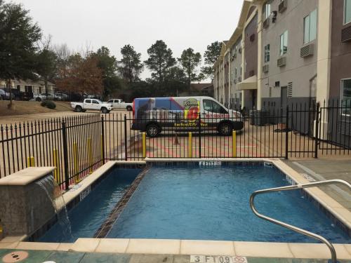 a van parked next to a fence with a small pool at Super 8 by Wyndham Bedford DFW Airport West in Bedford
