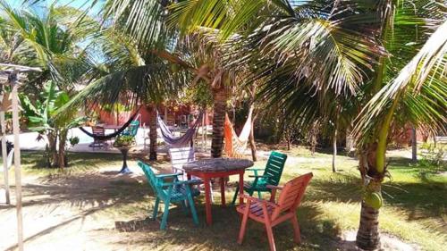 a table and chairs under palm trees with a hammock at Pousada A Vida é Bela in Águas Belas