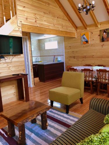 a living room with a tv and a couch and a table at Cabañas Los Laureles - Lican Ray in Licán Ray