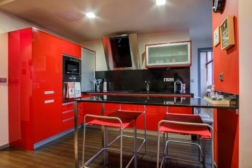 a red kitchen with red cabinets and bar stools at Casa Flor de Lis - T2 CENTRO in Braga