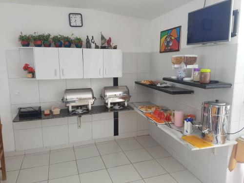 a kitchen with white cabinets and a counter with food at Pousada Privê Maré Alta in Porto De Galinhas