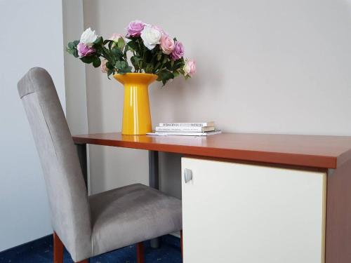a vase of flowers on a table with a chair at Hotel CITY in Prnjavor