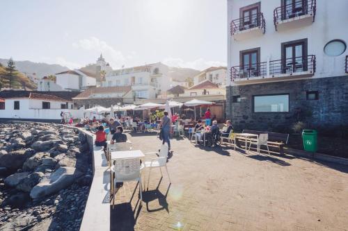 a group of people sitting at tables outside a building at Nature Madeira Guest House in Porto da Cruz