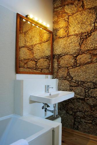 a bathroom with a sink and a stone wall at Quinta de Seves in Covilhã