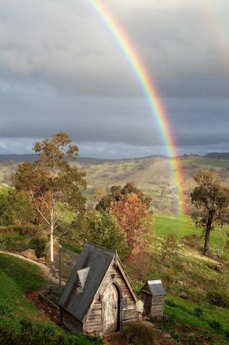 a rainbow over an old house in a field at Inspiring Views B&B in Wodonga