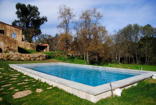 a large swimming pool in a field with a house at Quinta de Seves in Covilhã