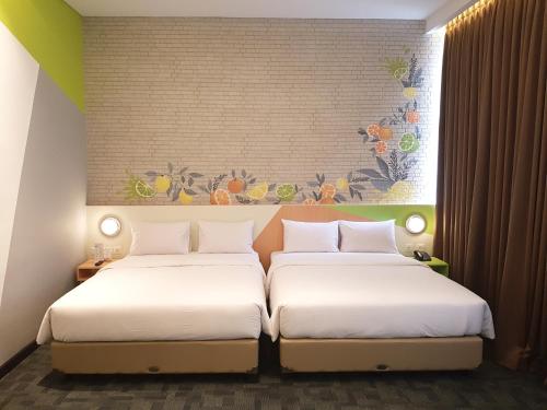 two twin beds in a room with a mural at Zest Sukajadi Bandung by Swiss-Belhotel International in Bandung