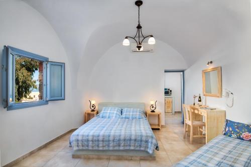 a bedroom with a bed and a desk and a window at Anatoli Hotel & Spa in Fira
