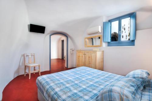 a bedroom with a bed and a window and a chair at Anatoli Hotel & Spa in Fira