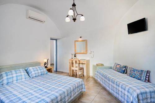 a living room with two beds and a tv at Anatoli Hotel & Spa in Fira