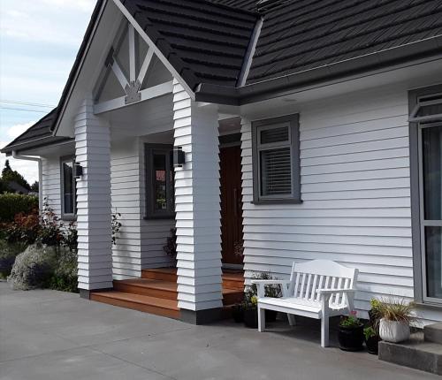 a white house with a bench on a porch at No. 6 Heathcote in Taupo