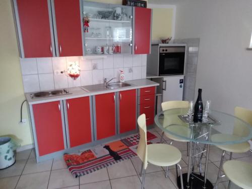 a kitchen with red cabinets and a glass table at Apartman Jurja in Ledenice
