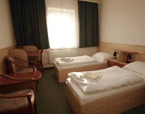ブルノにあるKolej Akademieのベッド3台と窓が備わるホテルルームです。