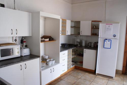 a kitchen with white cabinets and a refrigerator at Mr Pell's House Self-Catering Accommodation in Jeffreys Bay