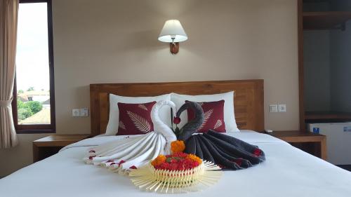 two swans are sitting on a bed with a bowl of flowers at Umayuri Inn in Ubud
