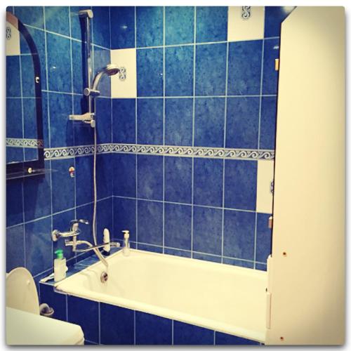 アルマヴィルにあるКвартираの青いタイル張りのバスルーム(バスタブ、シャワー付)